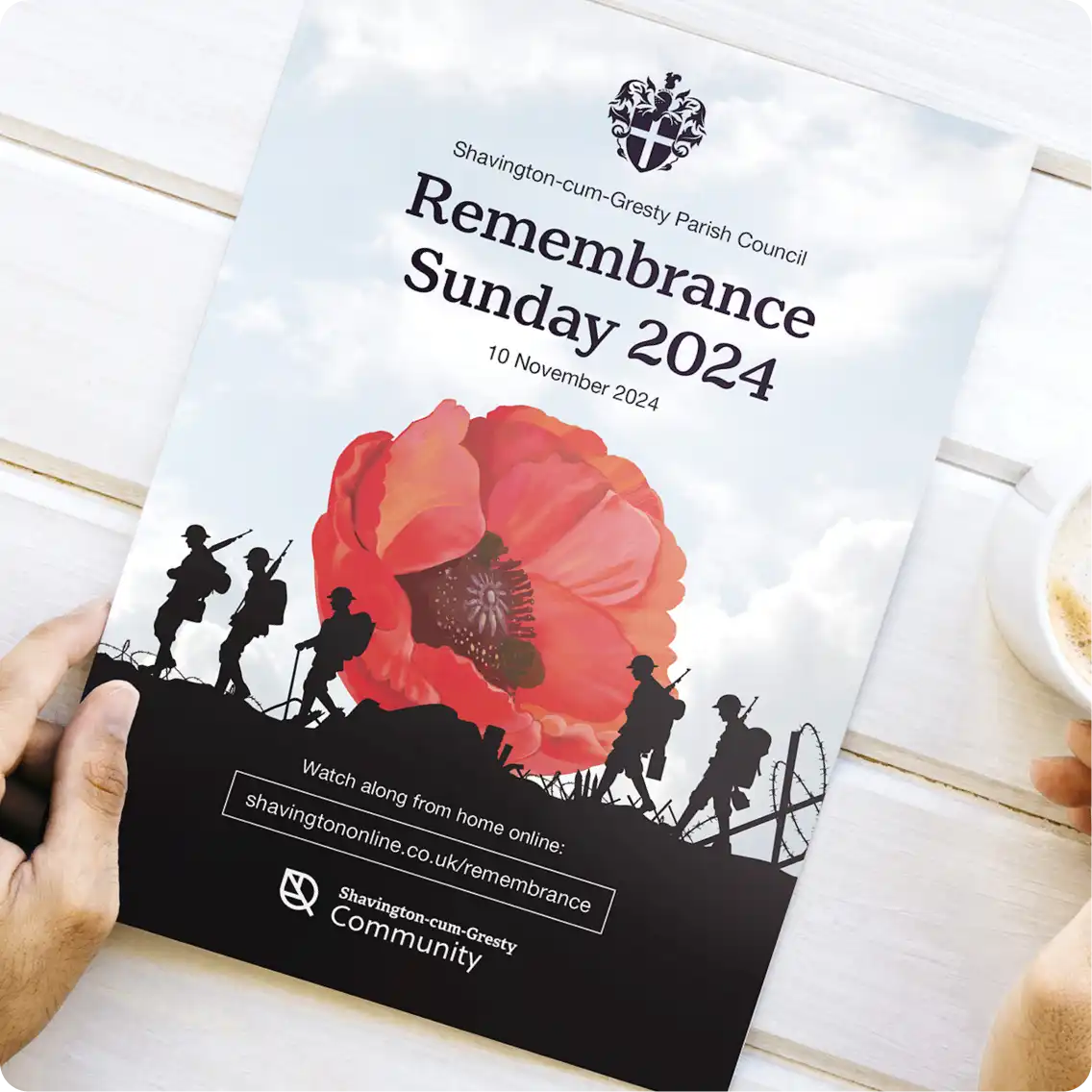 A hand holding a closed copy of the Shavington Remembrance Sunday booklet
